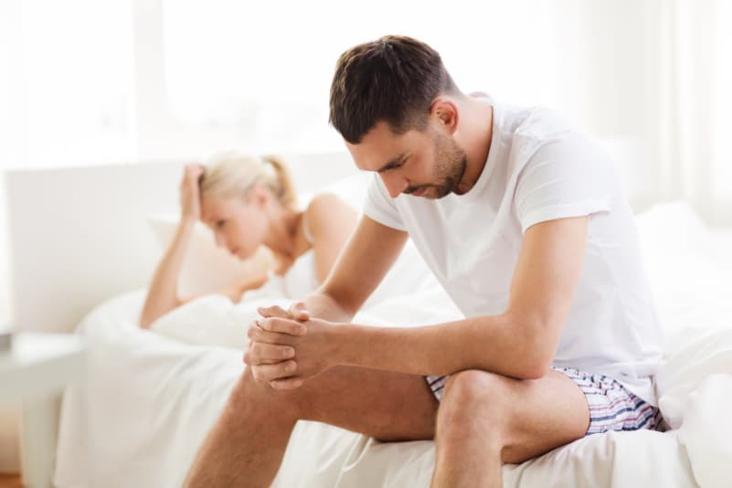 man in bed with woman looking disappointed