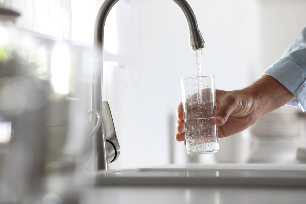 Man pouring water into glass in kitchen