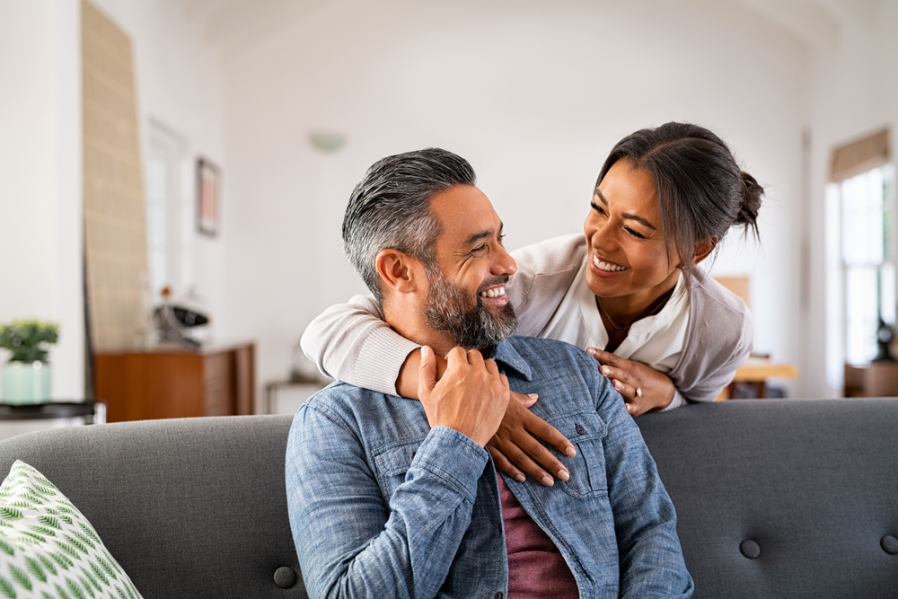 man and woman smiling at each other on couch