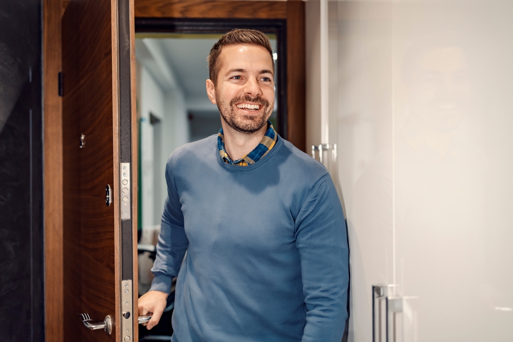 happy man is entering his house and shutting the door behind him.