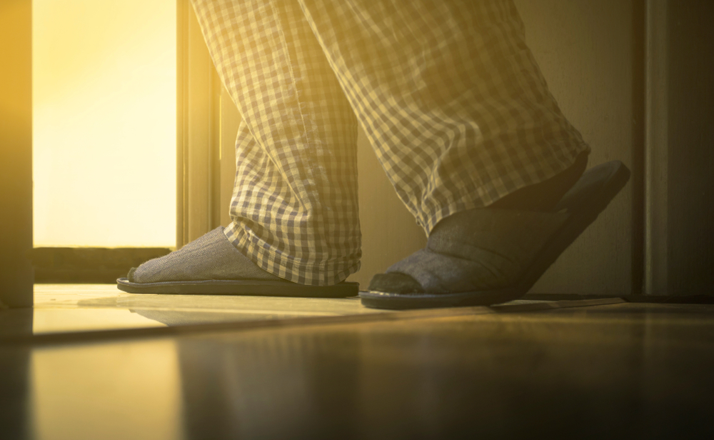 man in pajamas walks to a bathroom at night.