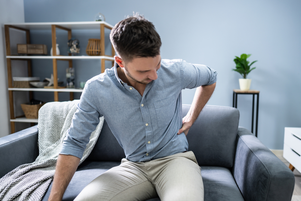 man on couch with lower back pain and kidney stones