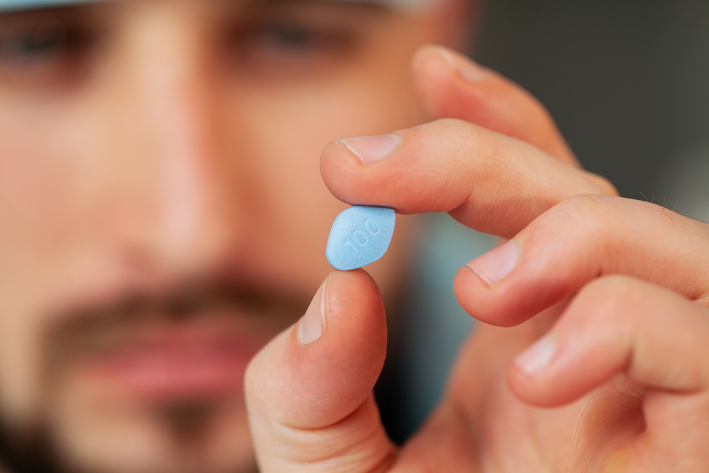 man holding little blue pill
