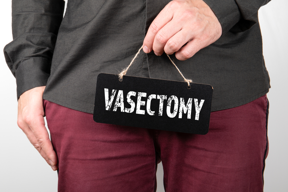 man holding a sign that says vasectomy.